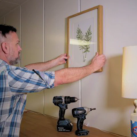Joel hanging a framed picture on a wall